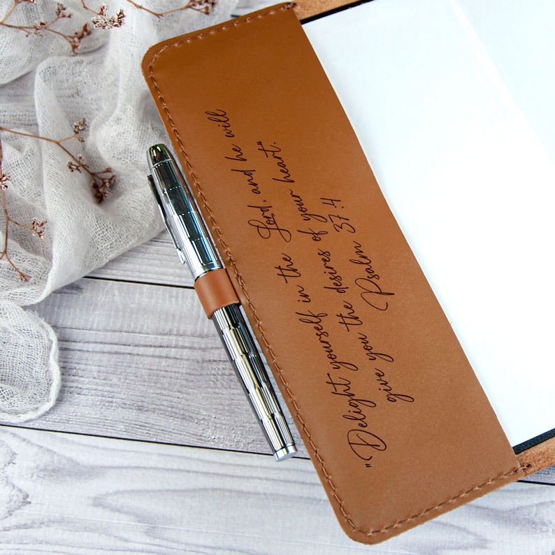 May include: A brown leather journal with a silver pen tucked into the leather strap. The journal has an engraved quote: "Delight yourself in the Lord, and he will give you the desires of your heart." Psalm 37:4