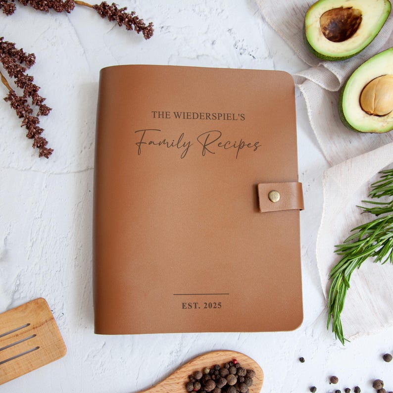 a leather-bound book titled "The Wiederspiel's Family Recipes" with a wooden spoon and various spices and ingredients surrounding it.