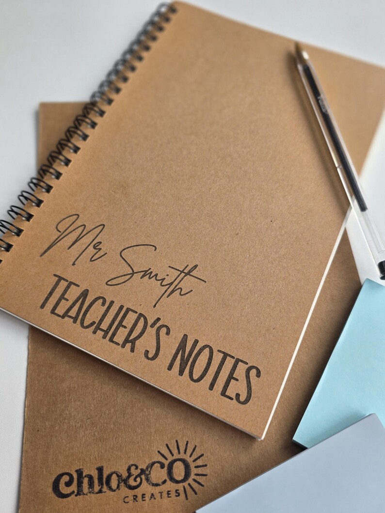May include: A spiral-bound notebook with a kraft paper cover. The cover is printed with "Mr Smith TEACHER'S NOTES" in black script and block letters. A pen and sticky notes are also visible.