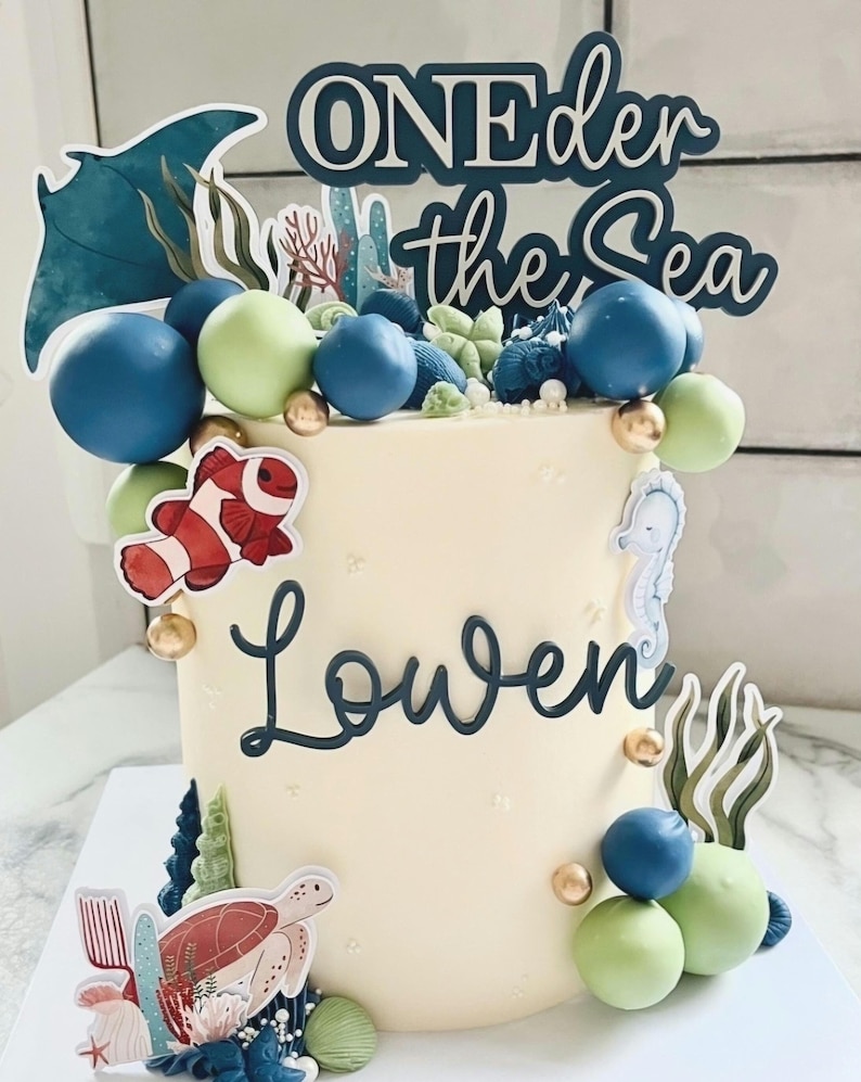 A modern double layer acrylic cake topper. It says Oneder the sea, to go with a first birthday with the under the sea theme