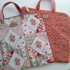 May include: Two fabric bags with patchwork designs. One bag is red with white floral print and the other is white with green, red, and pink floral patchwork. Both bags have brown leather tags.
