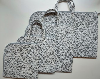 May include: Set of four gray zippered totes with a white and black cat print. The totes are different sizes and have gray handles.