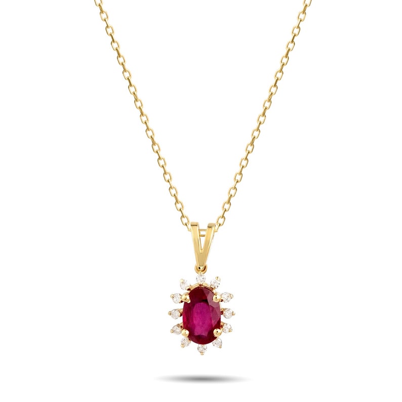 Op de afbeelding: Een gouden ketting met een hanger met een grote ovale robijn omringd door een halo van kleinere diamanten.