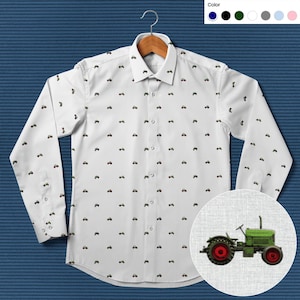 May include: White long-sleeve button-down shirt with a repeating pattern of small green tractors. The shirt is on a hanger and has a pocket on the left chest. A close-up of a green tractor is shown in the lower right corner.
