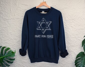 Könnte beinhalten: Ein marineblauer Pullover mit einem weißen Davidstern-Motiv und dem Text "Pray for Peace".