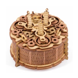 May include: A wooden birthday cake box with a decorative design and the words "Happy Birthday" engraved on the top. The box has a hinged lid and a small drawer inside. The box is made of light brown wood and has a natural finish.