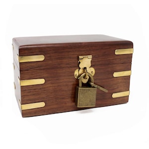 May include: A wooden box with a brass lock and key. The box is closed and has a dark brown finish. The lock is a simple padlock with a brass keyhole.