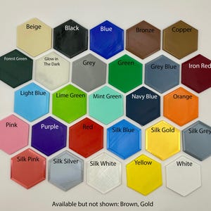 Puede incluir: Una carta de colores de 25 colores diferentes en forma de hex&aacute;gonos. Los colores incluyen beige, negro, azul, bronce, cobre, verde bosque, gris, verde, azul gris&aacute;ceo, rojo hierro, azul claro, verde lima, verde menta, azul marino, naranja, rosa, morado, rojo, azul seda, oro seda, gris seda, rosa seda, plata seda, blanco seda, amarillo y blanco. El texto "Disponible pero no mostrado: Marr&oacute;n, Oro" est&aacute; en la parte inferior de la carta.