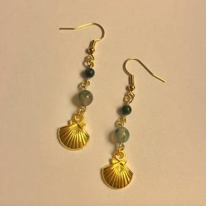 Könnte beinhalten: Goldene Muschel-Ohrringe mit grünen Achatperlen. Die Ohrringe sind im Hänge-Stil mit einem goldenen Haken.