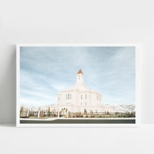 Könnte beinhalten: Ein weißer Tempel mit einer kupferfarbenen Kuppel vor einem blauen Himmel mit weißen Wolken. Der Tempel ist von einem grünen Rasen und einem schwarzen Zaun umgeben.