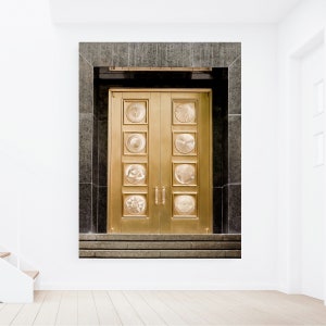 May include: A pair of large, golden double doors with intricate circular designs. The doors are set in a dark grey stone frame.