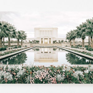 May include: A white building with a reflecting pool in front of it. The building has a large, arched entrance and is surrounded by palm trees and flowers.