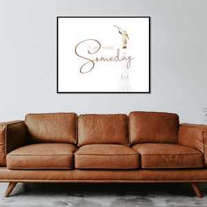May include: A white framed print with a brown text overlay that reads "I'll go inside someday". The text is in a cursive font. The image in the print is a white building with a golden statue of an angel on top. The angel is holding a trumpet.