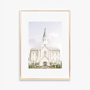 Puede incluir: Un edificio blanco con una alta aguja, rodeado de árboles y arbustos verdes. El edificio tiene un diseño simétrico con múltiples ventanas y una gran entrada.