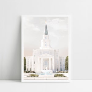 Può includere: Un tempio bianco con un'alta guglia e una fontana di fronte. Il tempio è circondato da alberi e cespugli verdi. Il cielo è azzurro chiaro con nuvole bianche.