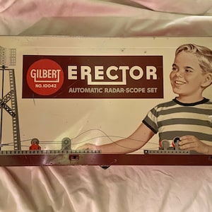May include: A vintage Gilbert Erector set box with a red and white logo and the text "Automatic Radar-Scope Set". The box features a young boy in a striped shirt holding a part of the set.