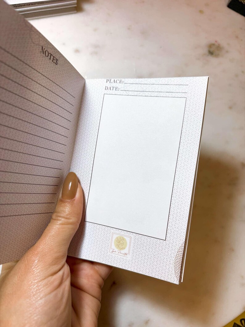 Op de afbeelding: Open notitieboek met gelinieerde pagina's en het woord "NOTES". Er is een sectie voor "PLACE:" en "DATE:" en een leeg vak. Het notitieboek heeft een patroonrand en een klein logo. De pagina's zijn wit en de kaft is lichtbeige.
