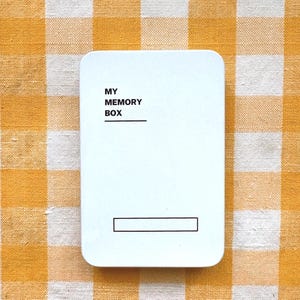May include: A white, rounded-corner rectangle with the text "MY MEMORY BOX" in black, and a horizontal line below "BOX". A rectangular box is below the line. The background is a yellow and white checkered pattern.