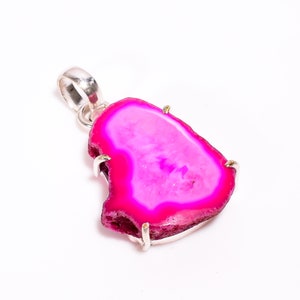 May include: A vibrant pink agate pendant with a silver bail. The polished stone has a natural, irregular shape and a bright, eye-catching color. The pendant is set in a silver metal frame.