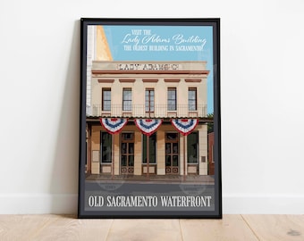 May include: A vintage-style illustration of the Lady Adams Building, the oldest building in Sacramento, California. The building is a two-story structure with a white facade and a red roof. The building has a balcony with a wrought iron railing. The building is decorated with American flags. The text "VISIT THE Lady Adams Building THE OLDEST BUILDING IN SACRAMENTO" is at the top of the image. The text "LADY ADAMEC" is on the building. The text "OLD SACRAMENTO WATERFRONT" is at the bottom of the image.