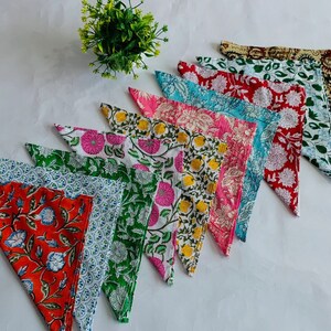 May include: A set of ten colorful cotton napkins with floral patterns. The napkins are folded into triangles and arranged in a fan shape.