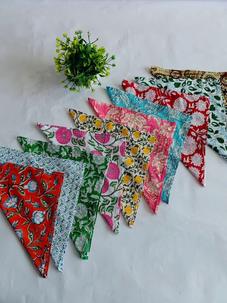May include: A set of ten colorful cotton napkins with floral patterns. The napkins are folded into triangles and arranged in a fan shape.