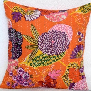 May include: Orange cotton pillow cover with a floral pattern in shades of purple, pink, yellow, and green. The pillow cover is quilted and has a unique, hand-stitched design.