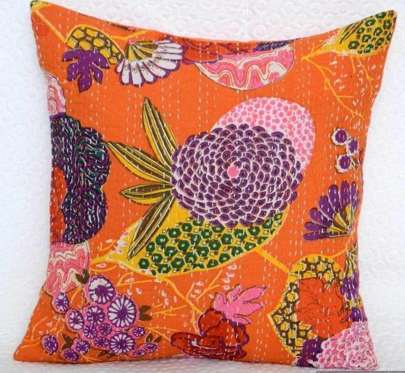 May include: Orange cotton pillow cover with a floral pattern in shades of purple, pink, yellow, and green. The pillow cover is quilted and has a unique, hand-stitched design.