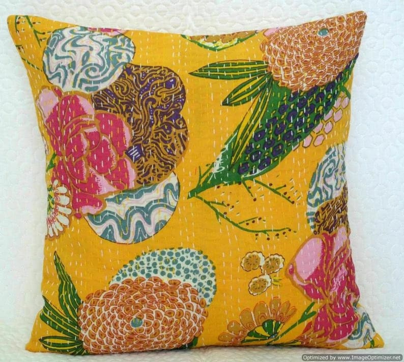 May include: Yellow cotton cushion cover with a floral pattern in shades of pink, green, brown, and blue. The pattern features large flowers, leaves, and swirls.