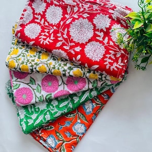 May include: A stack of five colorful cotton napkins with floral patterns. The napkins are in shades of red, yellow, pink, green, and orange.