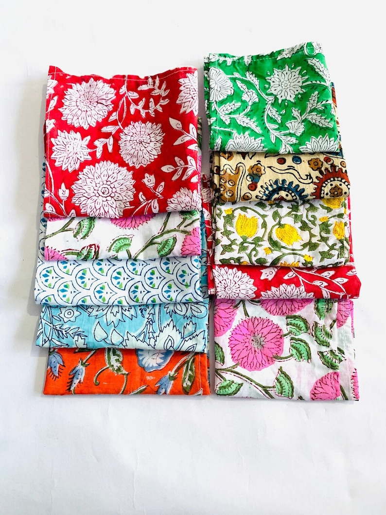 May include: A stack of 10 colorful cotton fabric squares with floral and geometric patterns. The squares are folded and arranged in two rows of five. The fabric is a mix of red, green, blue, yellow, orange, and pink.