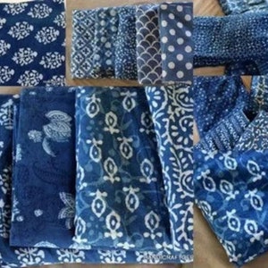 Puede incluir: Una colecci&oacute;n de cuadrados de tela azul &iacute;ndigo con varios patrones blancos. La tela est&aacute; doblada y apilada, mostrando diferentes dise&ntilde;os.