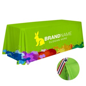 May include: A bright green rectangular tablecloth with a yellow rabbit logo and the text "BRAND NAME SLOGAN HERE." The bottom edge features colorful paint splatters. A close-up shows a corner with a star and stripe detail.