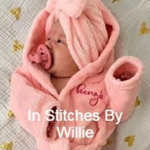 Peut inclure: Un b&eacute;b&eacute; portant un peignoir &agrave; capuche rose clair et une sucette. Le peignoir est brod&eacute; du nom "Renz's". Le texte "In Stitches By Willie" est &eacute;galement visible.