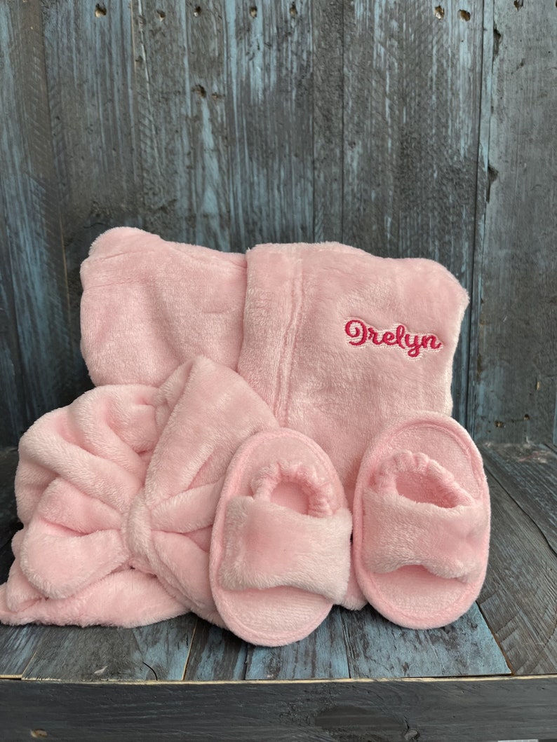 Peut inclure: Un ensemble de spa en peluche rose clair comprenant un peignoir, un bandeau et une paire de pantoufles. Le peignoir est brod&eacute; du nom "Orelyn" en fil rose assorti. L'ensemble est en mati&egrave;re douce et duveteuse.