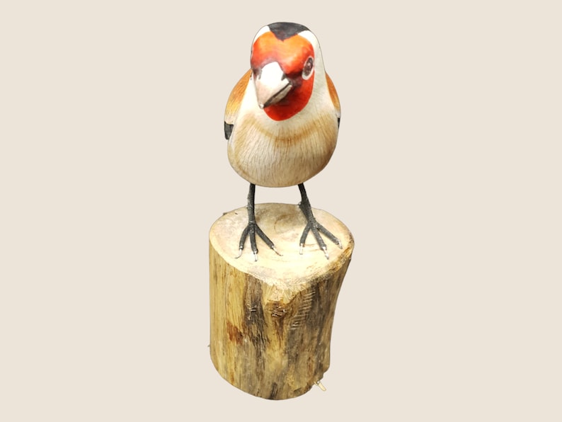 May include: Hand-carved wooden bird figurine with red, black, and white painted details. The bird is perched on a small wooden log.