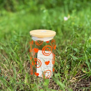 Vaso de cristal con cara sonriente de color naranja