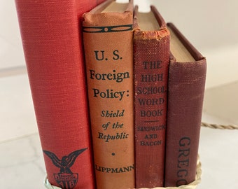 May include: A stack of five vintage hardcover books with red, brown, and orange covers. The books are tied together with a natural twine. The titles of the books are visible: "Accounting II", "U.S. Foreign Policy: Shield of the Republic", "The High School Word Book", "Sandwich and Bacon", and "Gregg Shorthand".