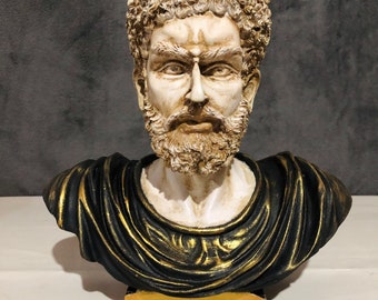 May include: A white bust sculpture of a man with a short, curly beard and hair. The bust is wearing a black and gold toga. The bust is on a gold base.