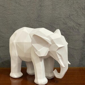 Op de afbeelding: Wit geometrisch olifant beeldje met een modern ontwerp. De olifant staat op een houten oppervlak.