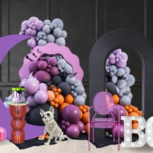 Halloween party event mockup made by a balloon artist and event planner. including light-up marqueeletters, a moon-shaped backdrop and a purple, black and orange balloon organic garland. Pumpkin prop, bats flying and and skeleton