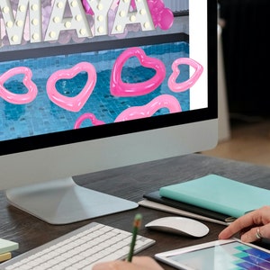 A balloon artist working on a mockup of a pink-themed indoor pool party event setup with large light-up marquee letters spelling "MAYA," a backdrop of pink and purple balloons, and heart-shaped pool floats in a pool