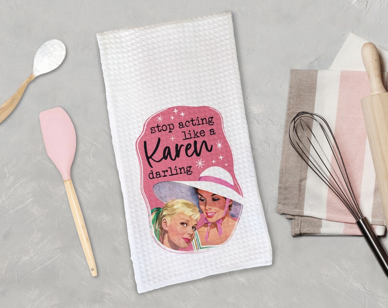 May include: White kitchen towel with a pink and white illustration of two women wearing hats. The text on the towel reads "stop acting like a Karen darling".