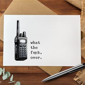 May include: A white greeting card with a black illustration of a walkie-talkie and the text "what the f*ck, over." The card is on a wooden surface with a pen and a burlap cloth.