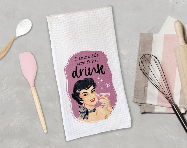 May include: White kitchen towel with a pink and white illustration of a woman holding a cocktail glass. The text on the towel reads "I think it's time for a drink."