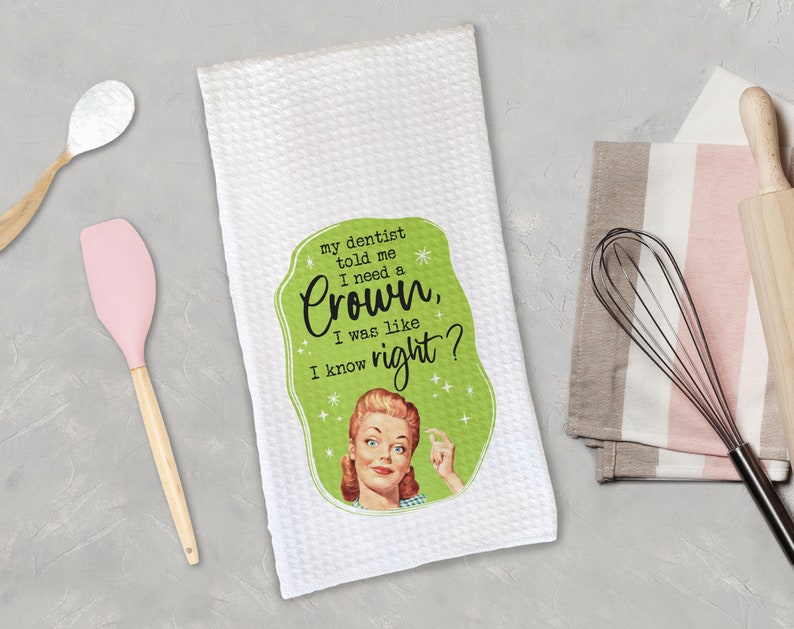 May include: White kitchen towel with a green and white design featuring a retro illustration of a woman with the text "my dentist told me I need a Crown, I was like I know right?"