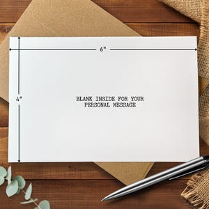May include: A white greeting card, 4 inches by 6 inches, with the text "BLANK INSIDE FOR YOUR PERSONAL MESSAGE" printed in black. The card is on a brown envelope, with a silver pen nearby.