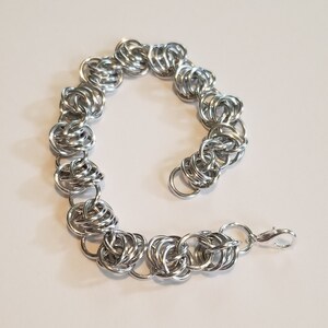 Könnte beinhalten: Ein silbernes Kettenarmband mit einem Verschluss. Das Armband besteht aus ineinandergreifenden Ringen.
