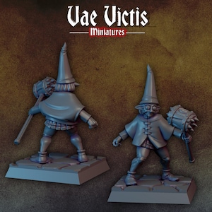 May include: Two grey miniature figurines of a goblin-like creature wearing a pointed hat and a short cape, holding a spiked mace. The figures stand on square bases. The text Vae Victis Miniatures is displayed at the top of the image.