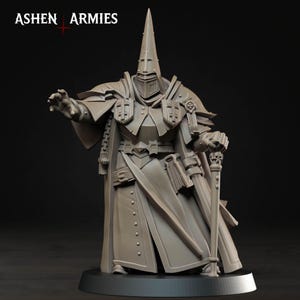 Può includere: Una miniatura in resina grigia intitolata ASHEN ARMIES, che raffigura un personaggio in tunica con elmo a punta e armatura. La figura tiene un bastone sormontato da un teschio, presenta un libro in vita e ha una mano tesa in avanti.